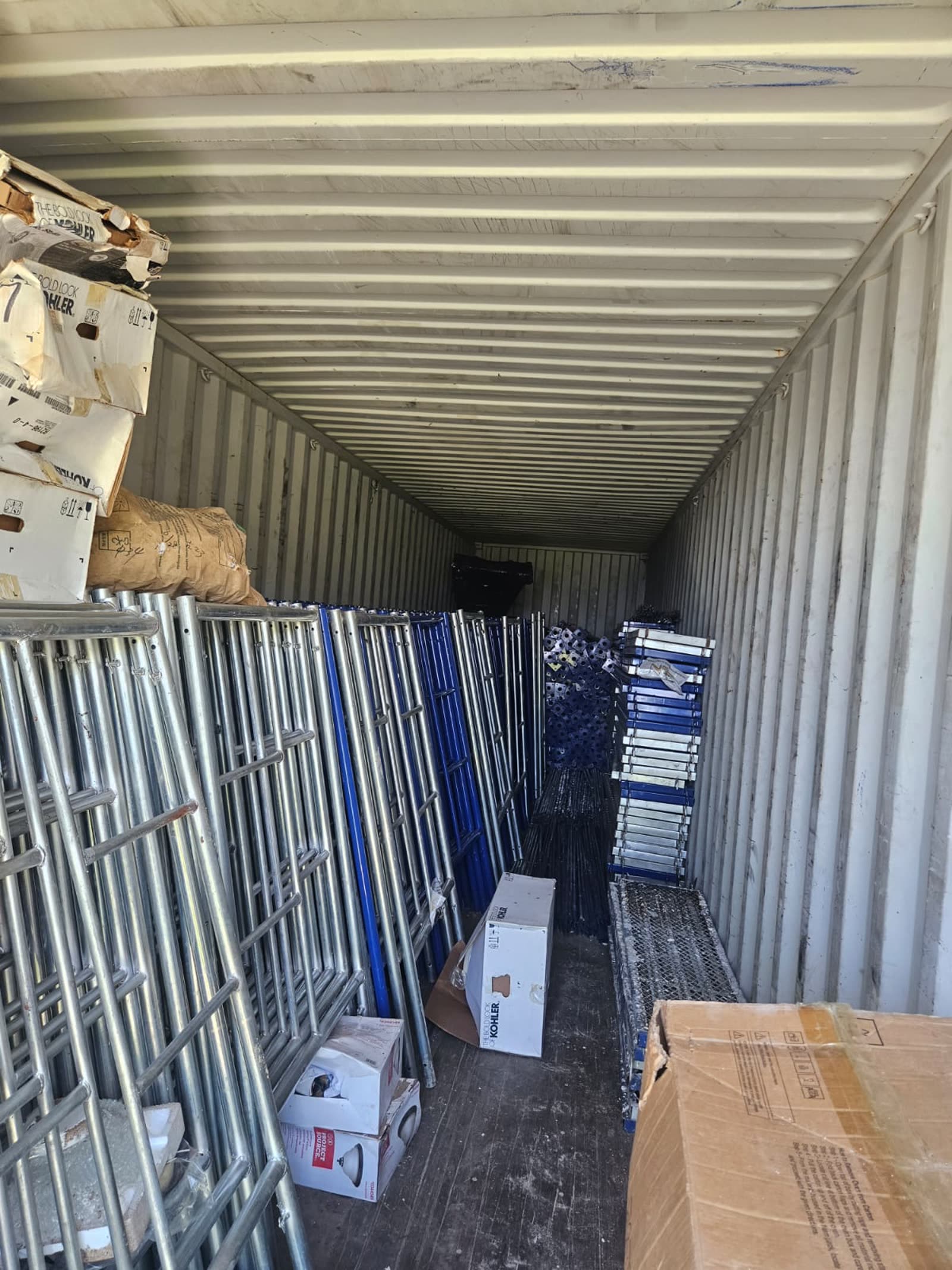 Silver and blue scaffolding frames stacked in the KBS storage container